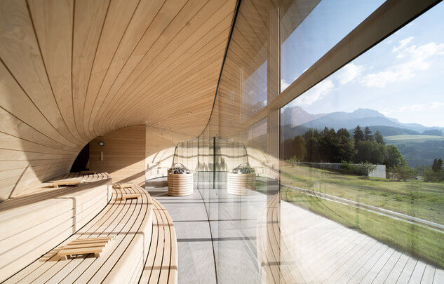 Modern gestalteter Wellnessbereich mit Holzbank und großer Glasfront zum Ausblick.