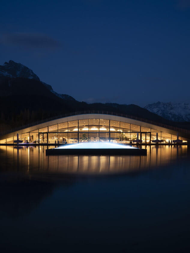 Moderne Architektur am Wasser in Zell am See mit stimmungsvollem Licht und Bergen im Hintergrund.