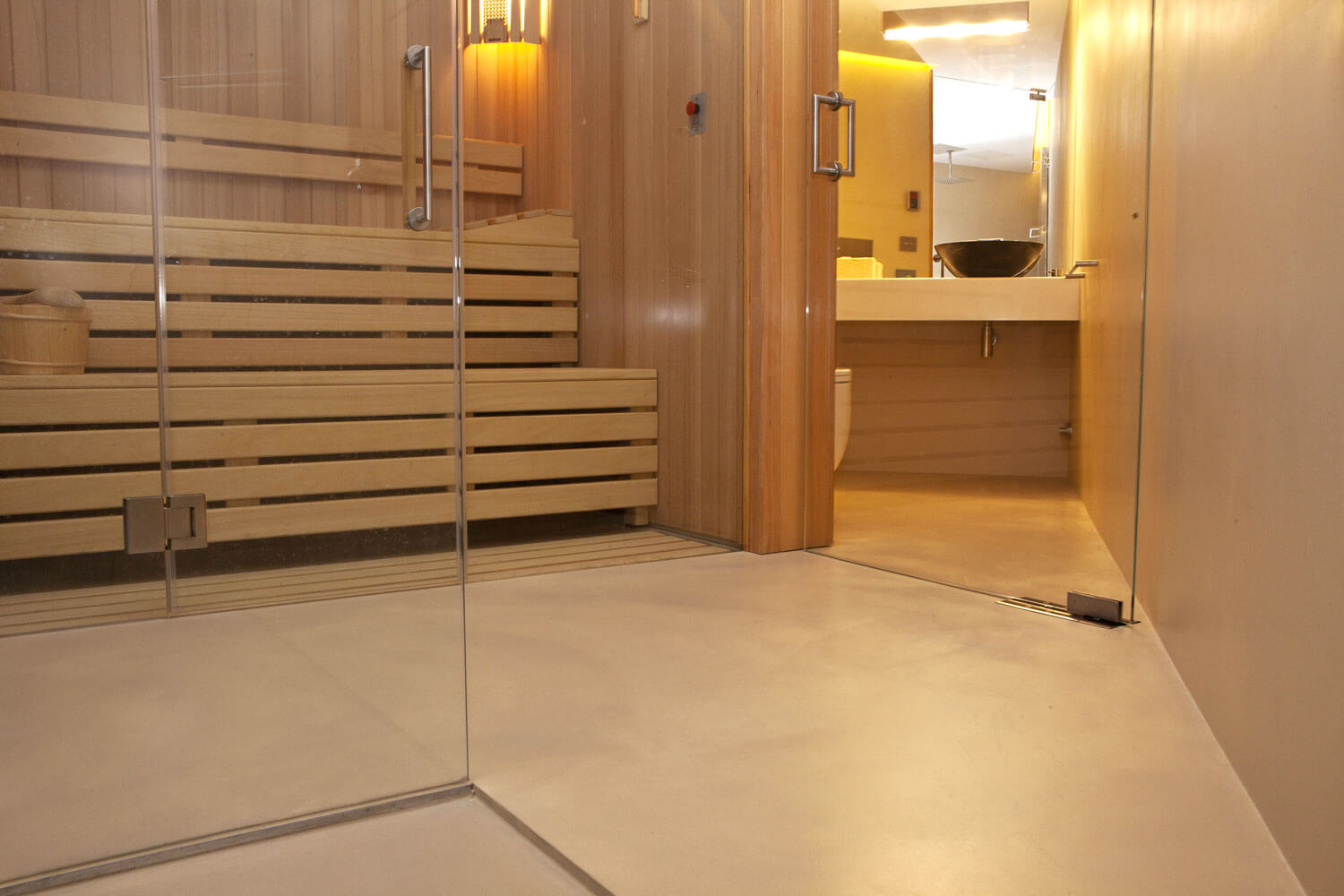 Fugenlose Oberfläche in einem modernen Bad mit Sauna-Elementen und eleganten Holzverkleidungen.