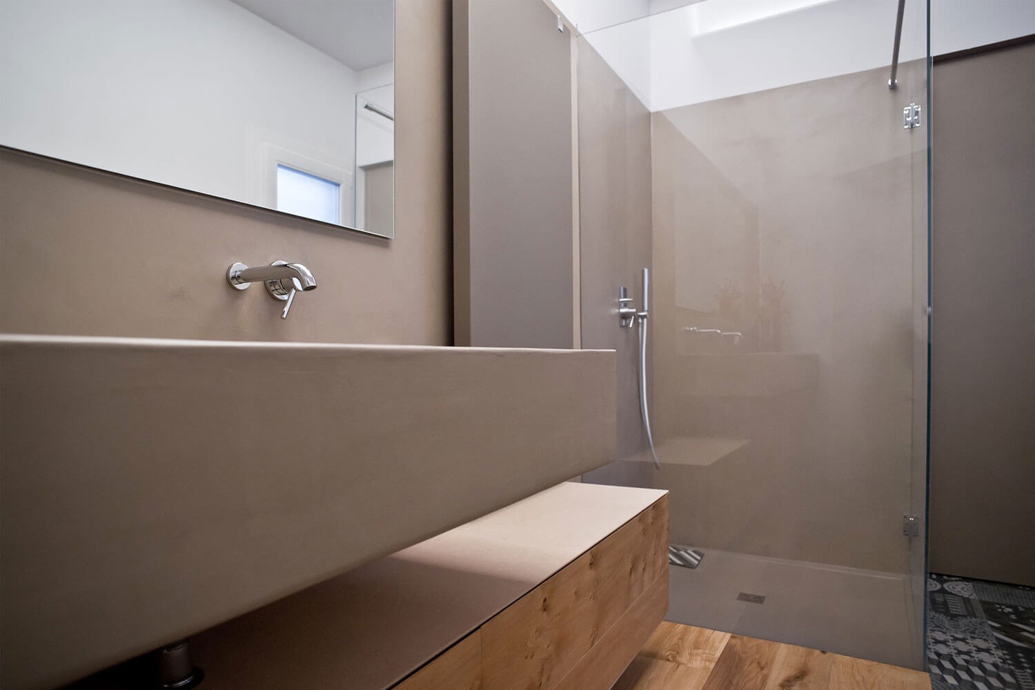 Moderne Dusche mit fugenloser Oberfläche und minimalistischem Waschbecken aus Holz.