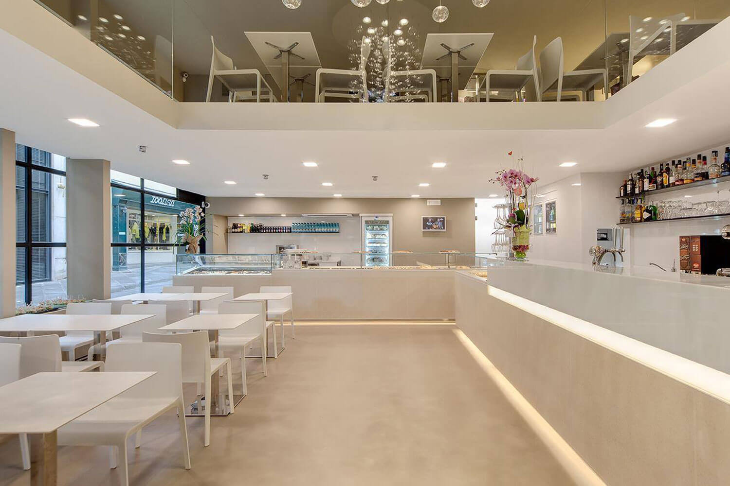 Modernes Café mit eleganter Bar, hellen Möbeln und stilvoller Dekoration.