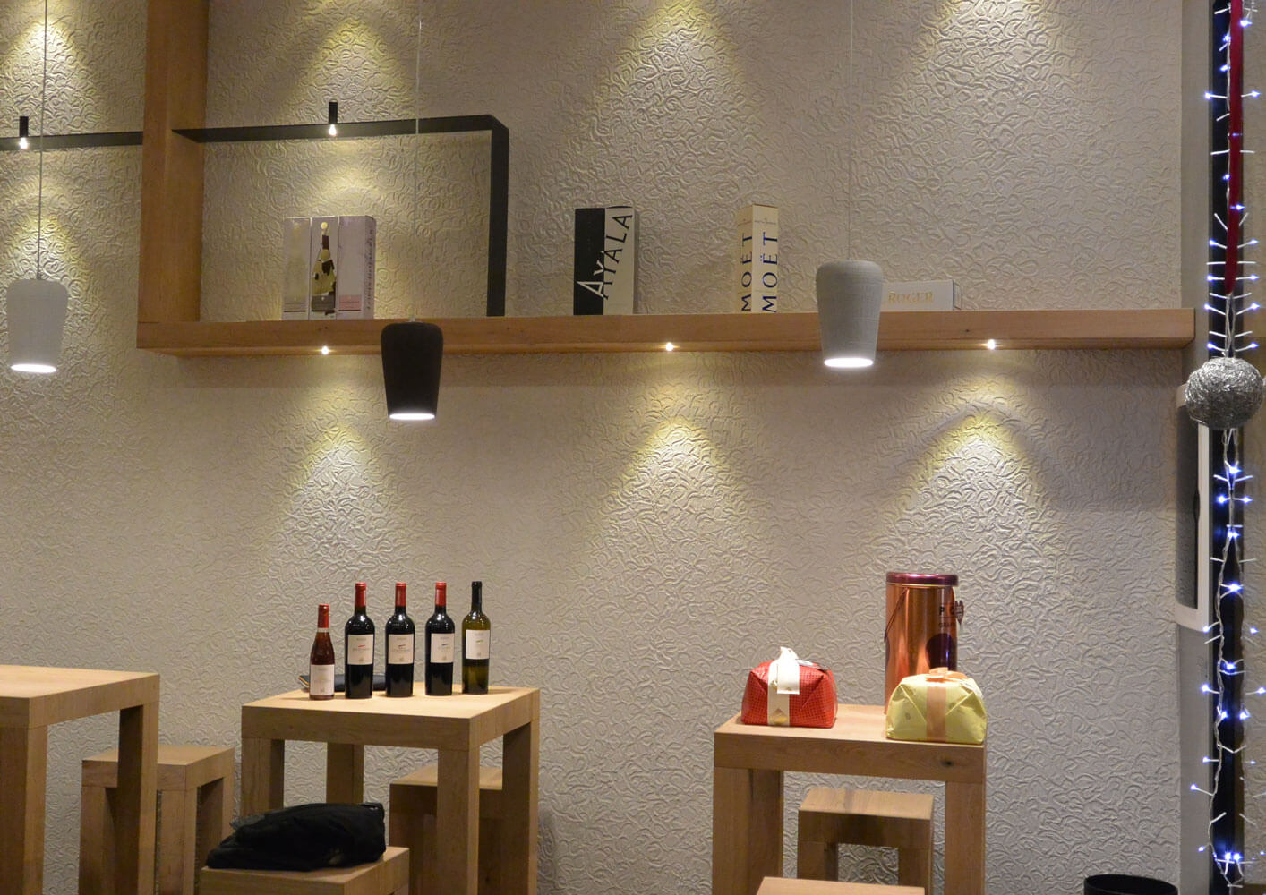 Moderne Beleuchtung und Weine auf Holzregalen in stilvollem Raum, ideal für Beratung und Design.