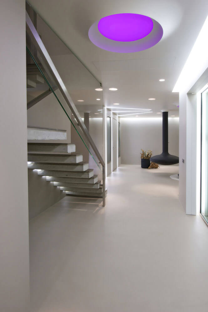 Modernes Foyer mit fugenlosem Boden, Glastrennwänden und lila Deckenbeleuchtung.